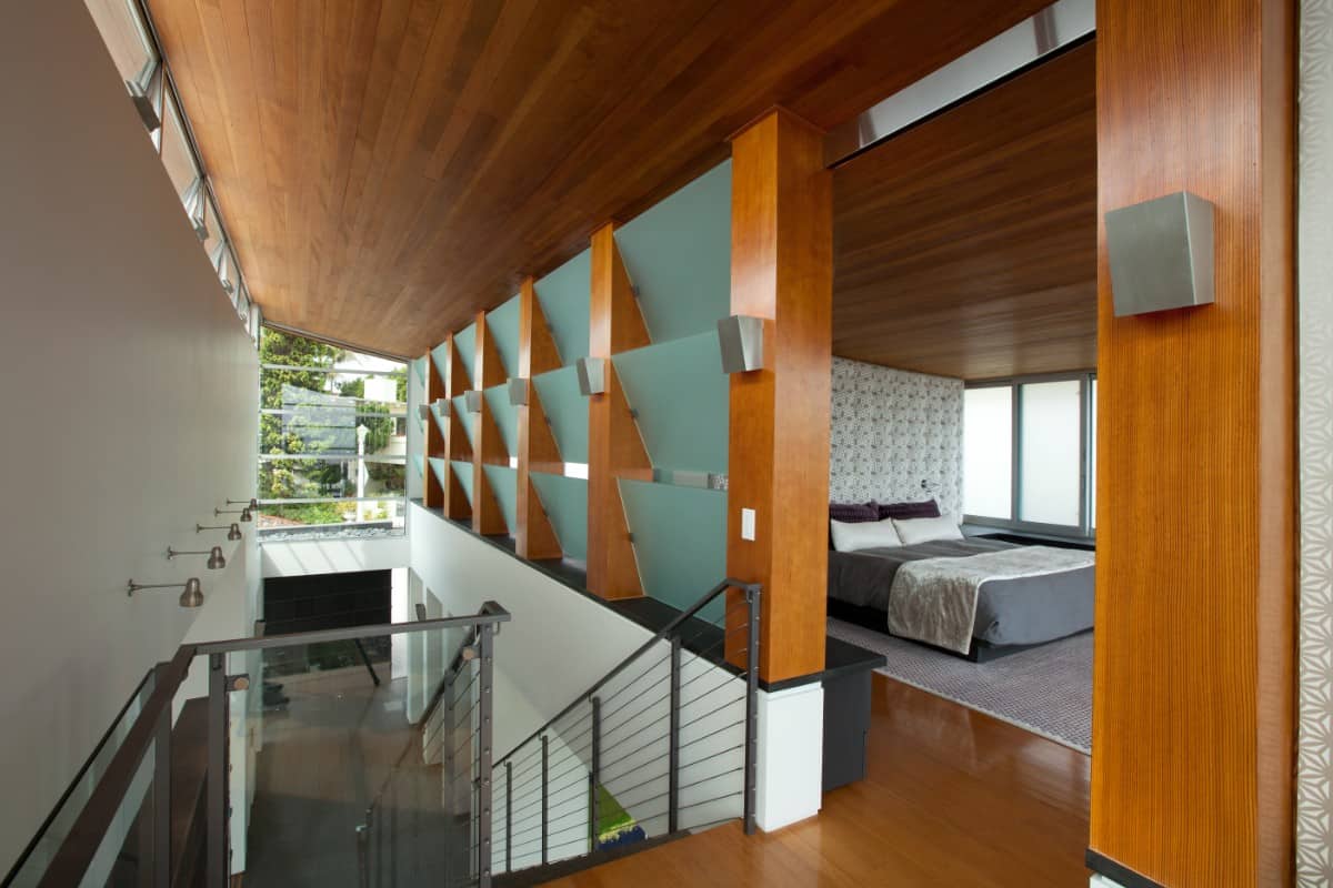 The bedroom is located on the top level. It is encased in glazed walls and slatted glass windows.