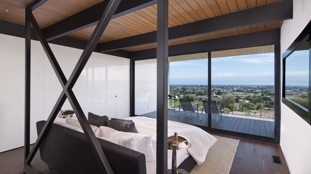 The bedroom offers a detailed view of its design and features, including the ability to take in the stunning views of the surrounding landscape through the use of full-height glass windows.