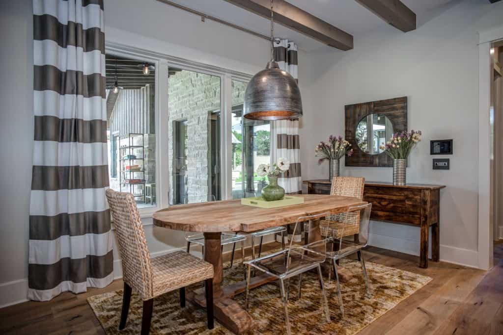 The breakfast nook has an oval dining set, a wooden buffet table, and a view of the covered porch.