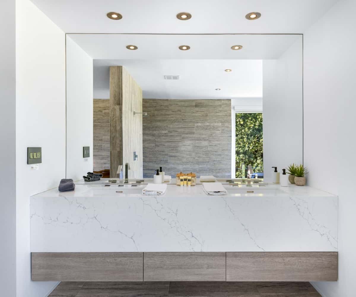 The primary bathroom's vanity with marble counter and a large frameless mirror.