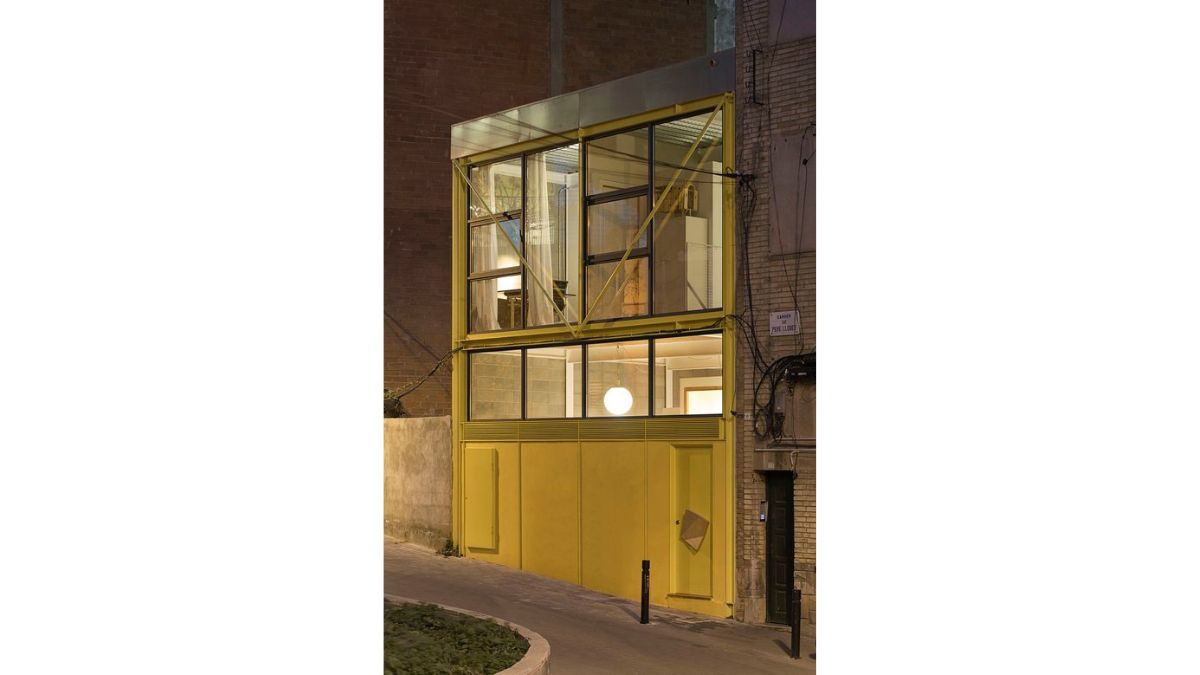 The side perspective of the house is made using a yellow-painted wall and a large window panes.