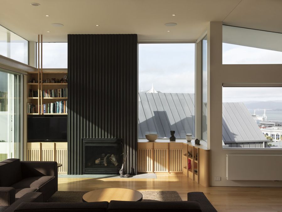 An interior photograph of the living room located on the upper floor, highlighting the use of vertical lines in the design elements on the fireplace such as the corrugated zinc clad.