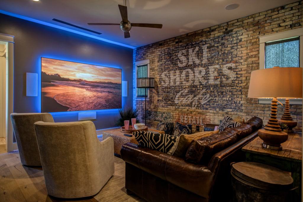 The home theater boasts a striking brick accent wall and a large TV highlighted by led lights.