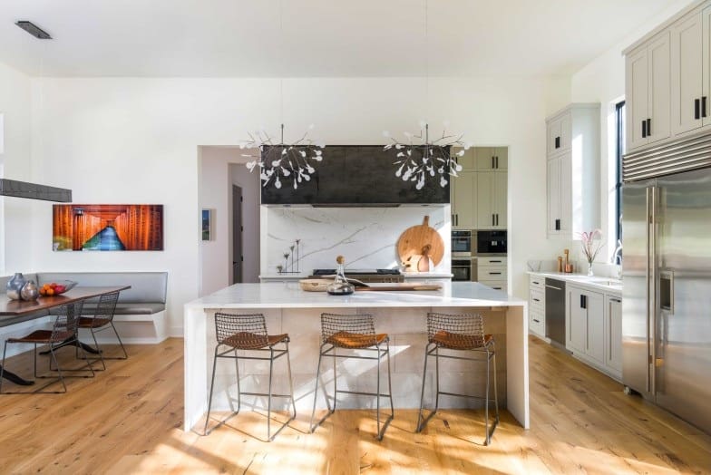 The kitchen offers ample storage, a waterfall island, and an adjoining dining nook with banquette seating.