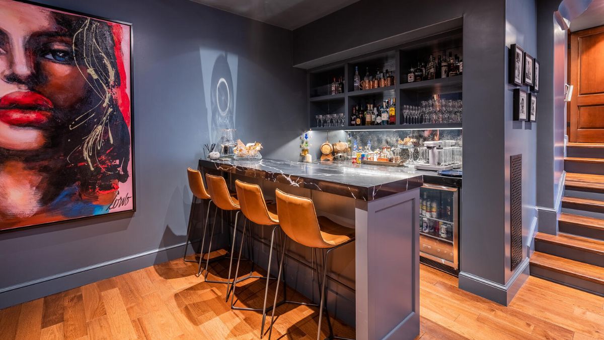 This tiny bar is located in the media room and has a fiber tile table, four stools, and a cabinet with a variety of liquors and glasses.