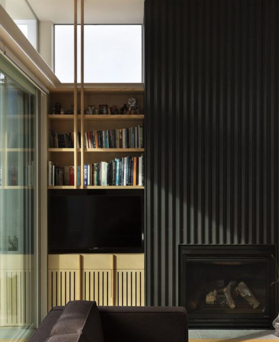 A close-up photograph of the fireplace and American ash bookcase, emphasizing the use of vertical lines in the design elements and its continuity with the building's vertical exterior cladding.