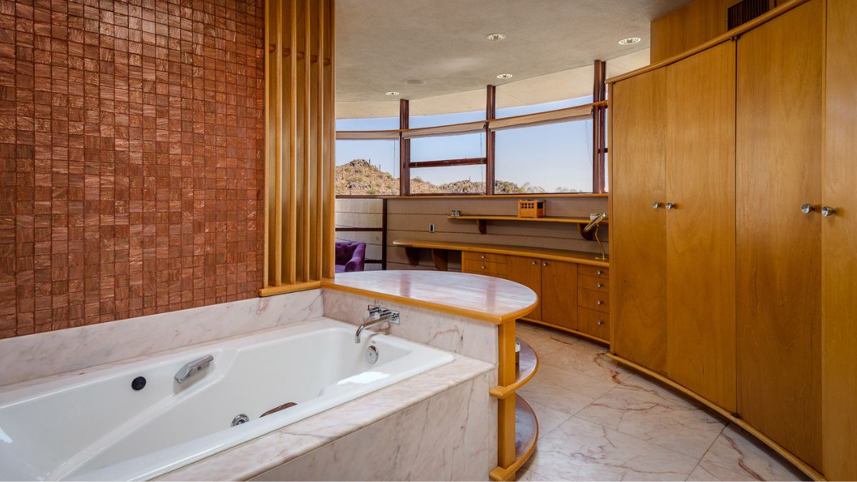 The master bathroom has a white and tidy bath tub on one side and oak cabinets on the other.