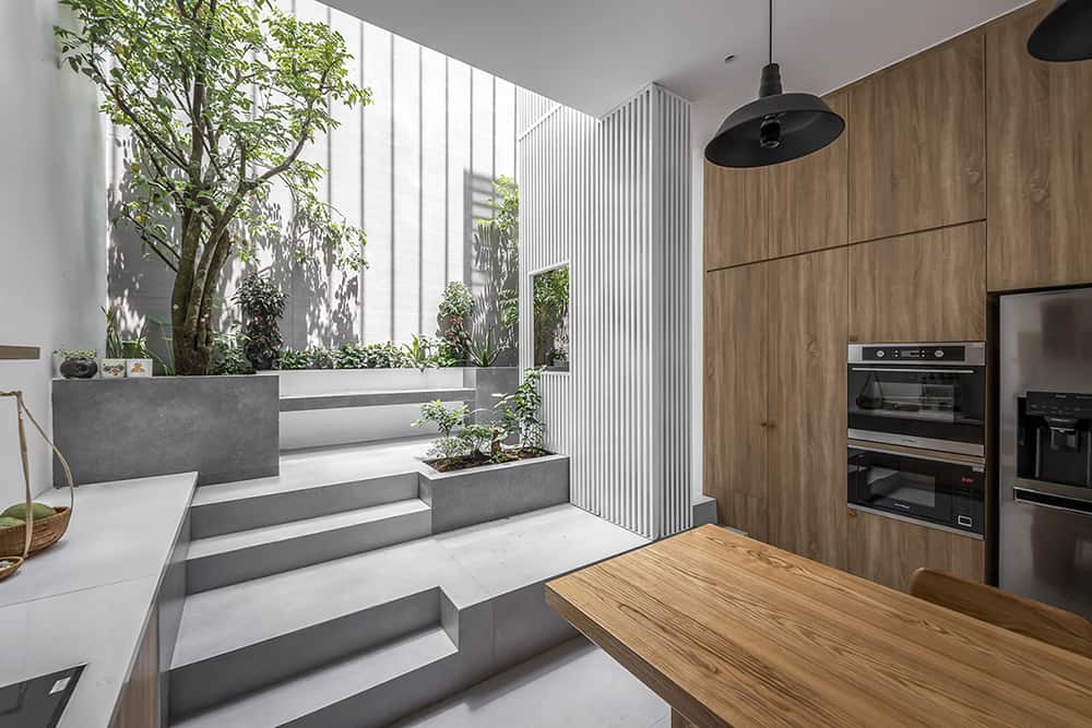 A multi-level staircase separates the atrium from the kitchen space.