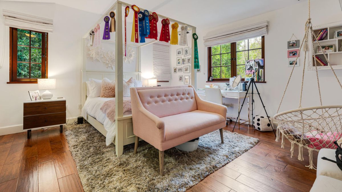 This compact, bright bedroom features carpet for the bed and a tiny couch, plus windows that let in light.