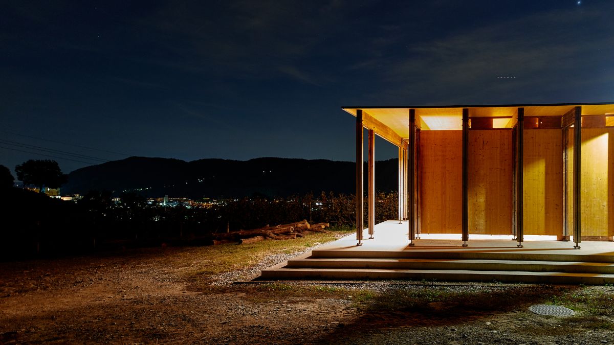 A nightscape of the pavilion with the lights turned on, showing the city lights in front