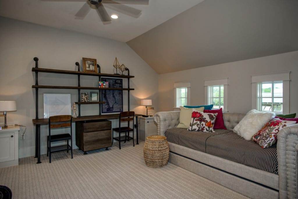 The bonus room offers a large chesterfield sofa and a lengthy desk paired with two iron chairs.