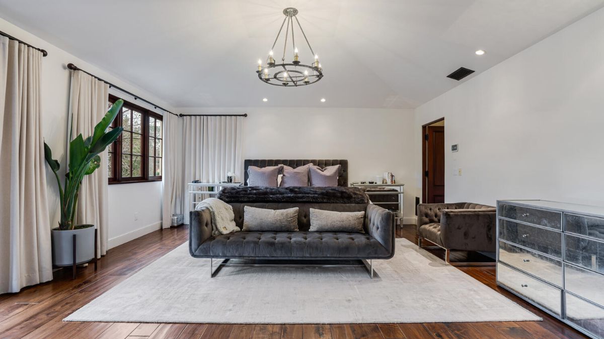 With a velvety gray bed, a couch, and a window covered in long, exquisite drapes, the master bedroom exudes an air of elegance and wealth.