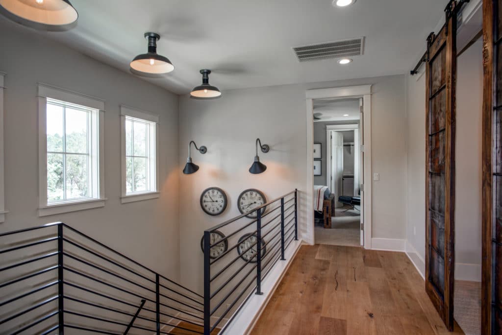 Hallway on the top floor with hardwood floor and wrought iron railings.