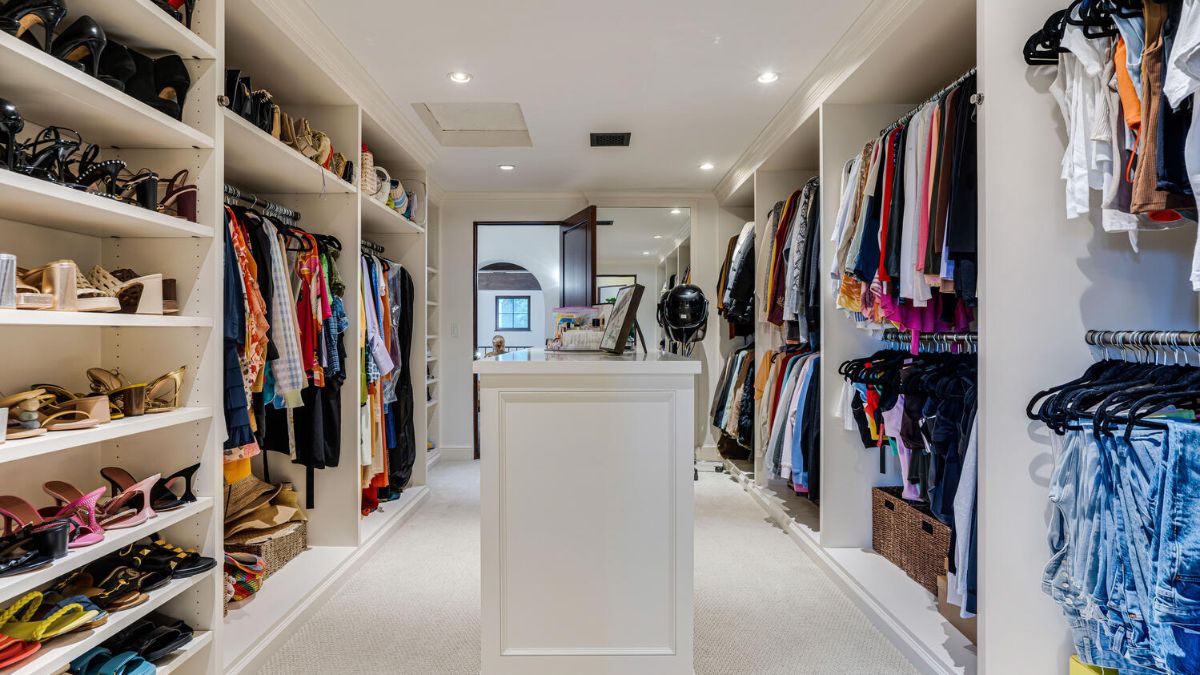 A sizable walk-in closet with a brightly lit, all-white interior.