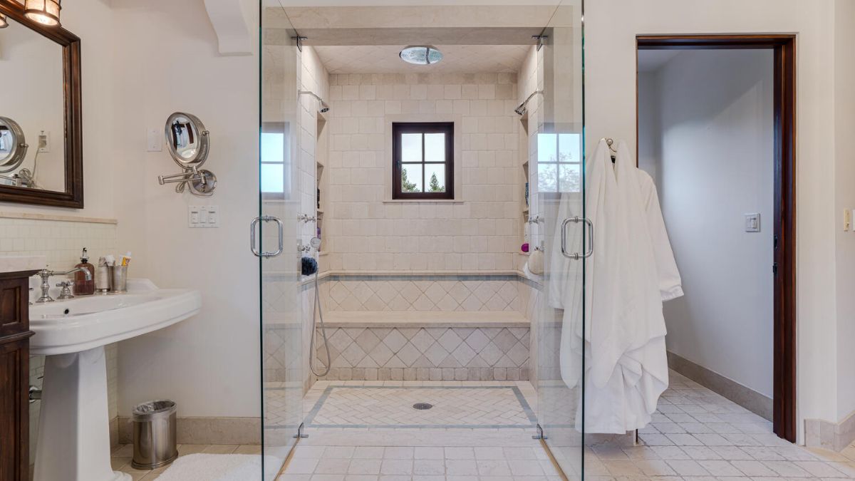 Master bathroom with white tiles and a glass door separating the shower.