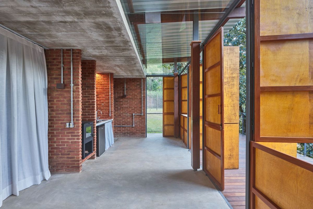 The house is made of bricks and plywood panels that open at two different heights like a traditional system of farm doors.