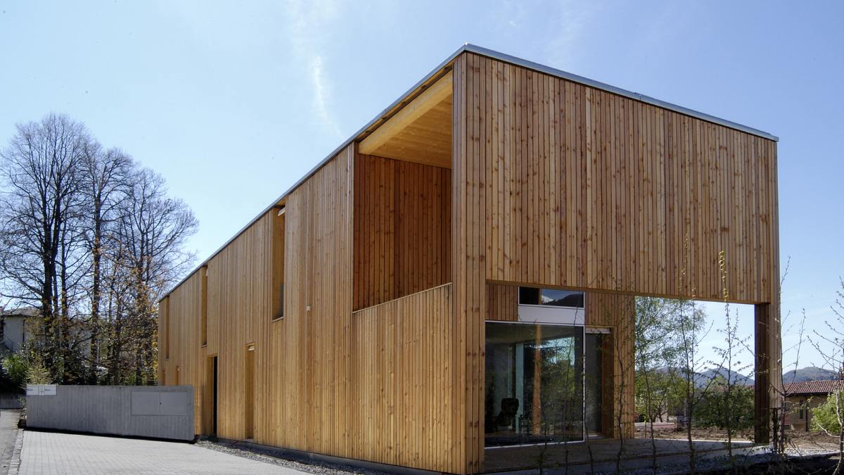 A view of the back of the building displaying a wall made of vertical planks of nordic larch, with windows at odd intervals