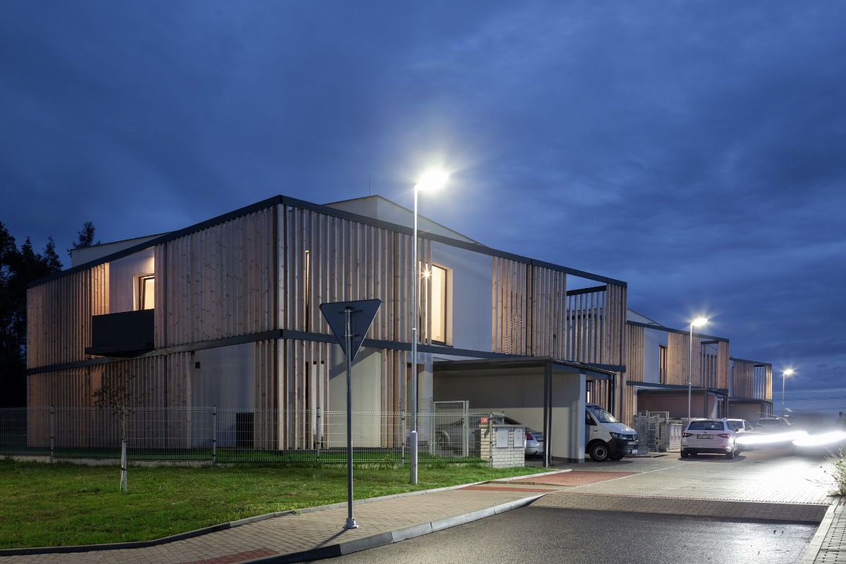 A nighttime view of three simple cube semi-detached houses in the vicinity of the capital city.