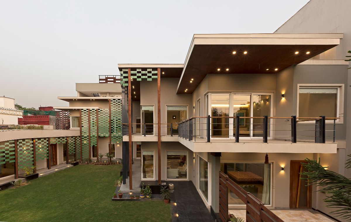 A bungalow house in stacked low-rise volumes around a manicured lawn intended for social gatherings.