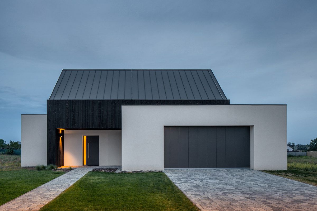 The house's side facade is made of metal roofing and white plaster materials.