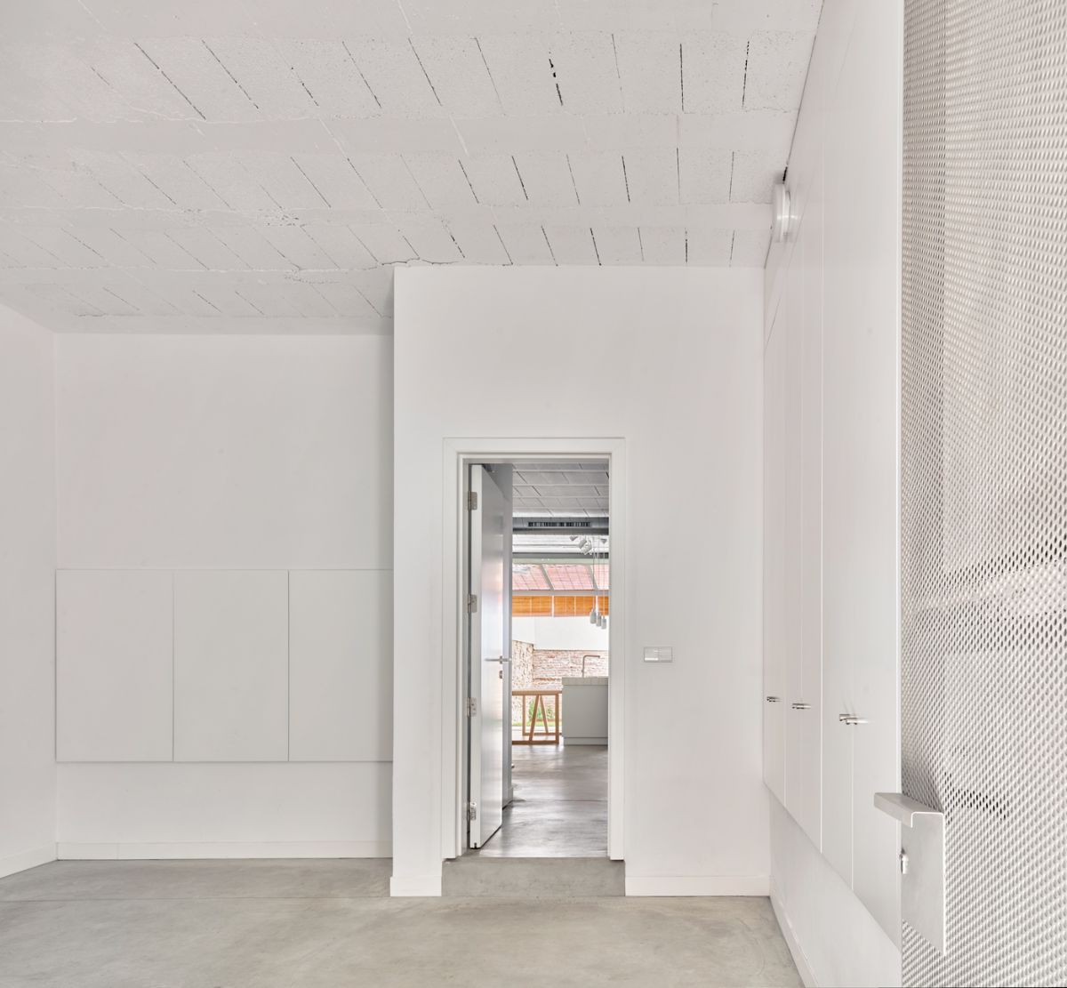 In the entrance is an empty foyer with an open exposed concrete floor.