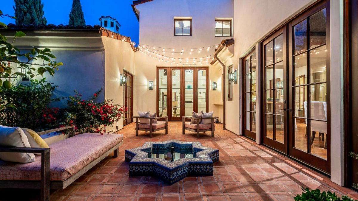 A nighttime picture of the outside with couches and chairs and lovely series of lights.