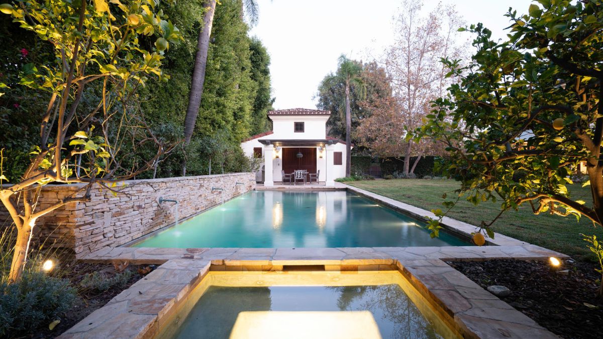 A stunning pool with a jacuzzi that is rectangular in design and illuminated.