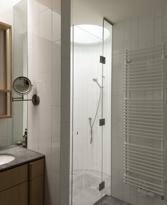 An interior shot of the bathroom focusing on a simple material's palette leading to the shower area.