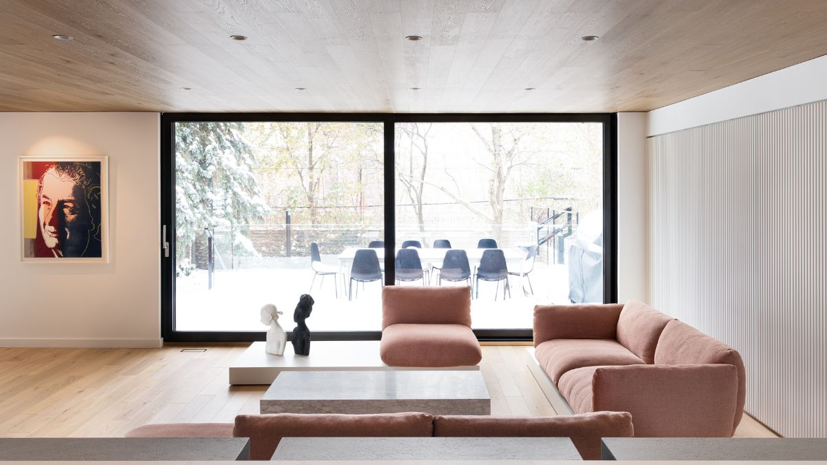 A wide-angle shot of a living room featuring a full-height glass door, offering a view of the expansive outdoor patio.