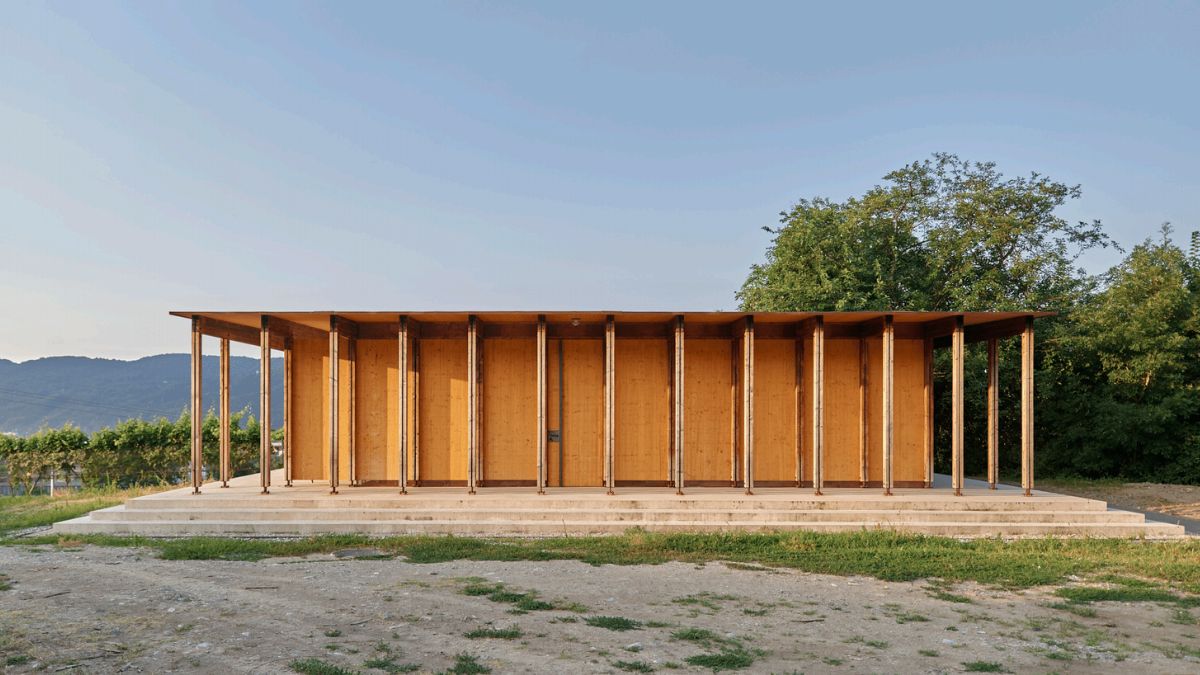 A view of the building from the south, showing its wooden wall and supported by pillars.