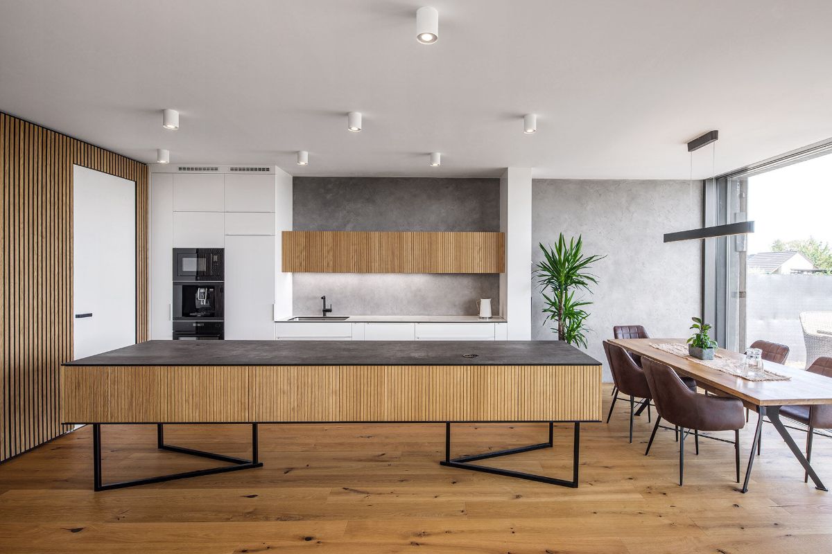 An open kitchen and dining area with a floor-to-ceiling glass wall that allows for natural ventilation.