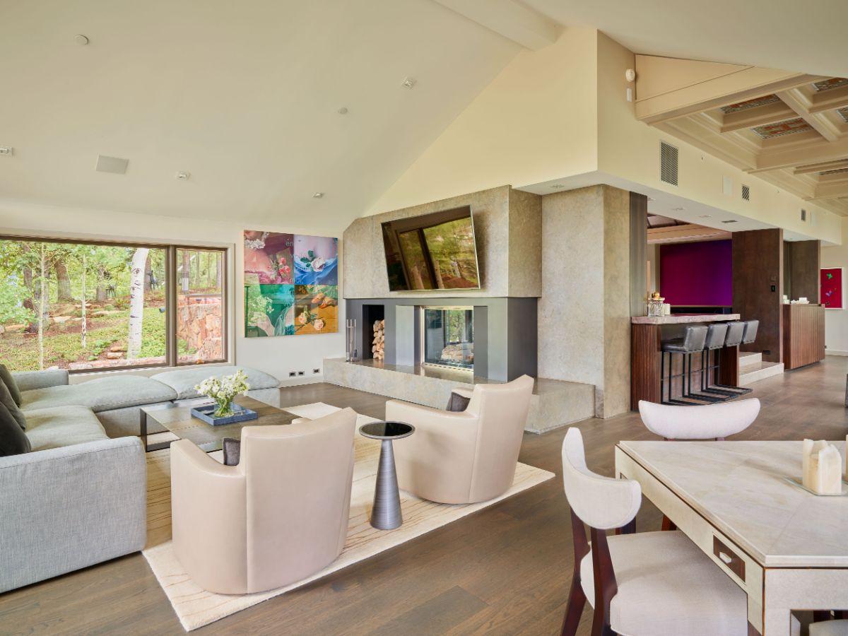 A living room with a real wood-burning fireplace and a full-width glass window that brightens the space. Image courtesy of Toptenrealestatedeals.com