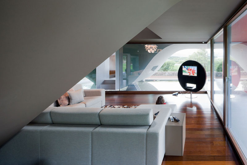 The living room is enclosed with glass walls that overlooks the wing of the house.