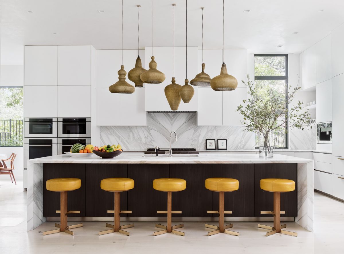 An opulent kitchen with a marble-topped island and pendant lights.