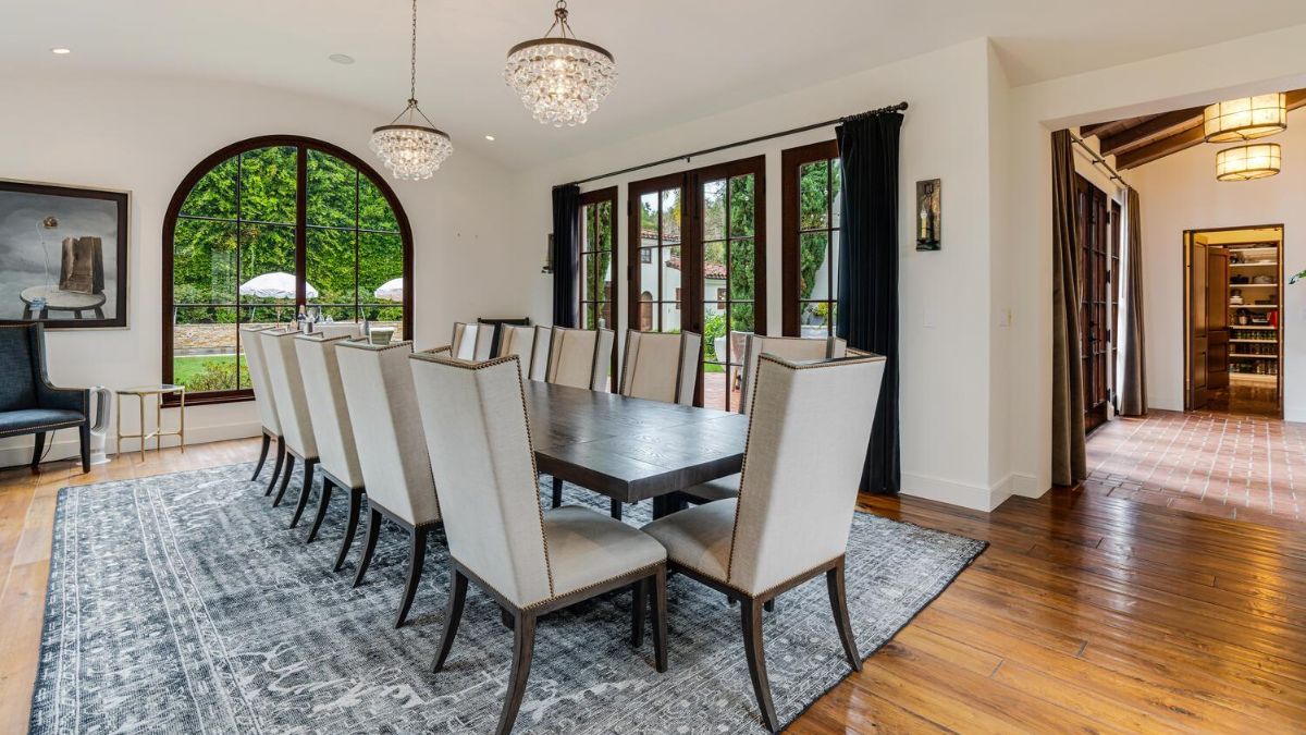 This master dining room includes two elegant chandeliers, hardwood flooring with carpet, and more seating than the previous one.