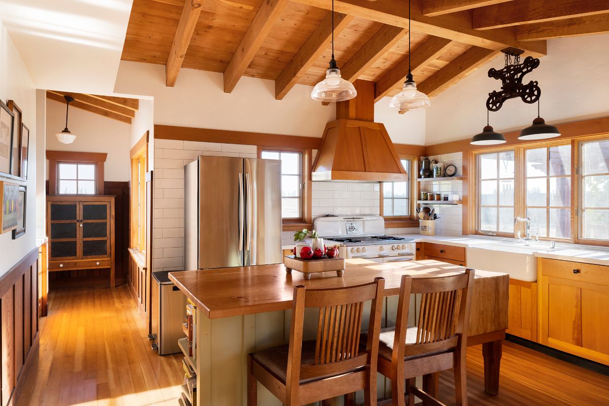 The bi-level kitchen island has a wooden countertop blending well with other antique furniture creating a rustic feel in the room.