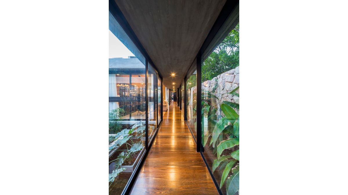 The long interior corridor is made out of large transparent frames and hardwood flooring that leads to various interior areas while allowing views of the property's outdoor spaces.