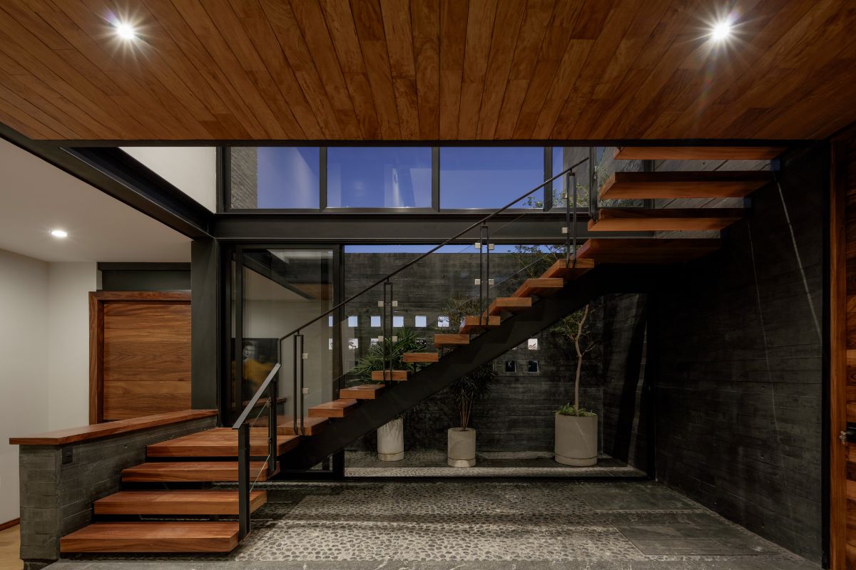 The wooden U-shaped staircase leads to the bedrooms upstairs.