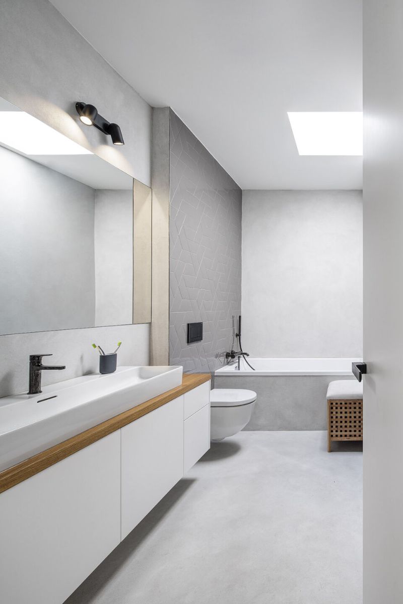 The main bathroom, complete with a bathtub. White plaster and tanned wood are the primary materials.