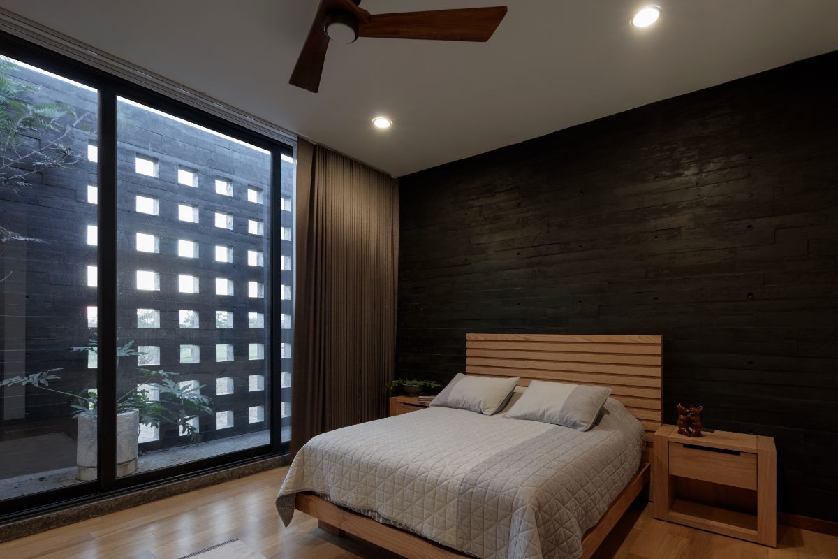 A black bedroom with glasswalls and curtain to regulate sunlight.