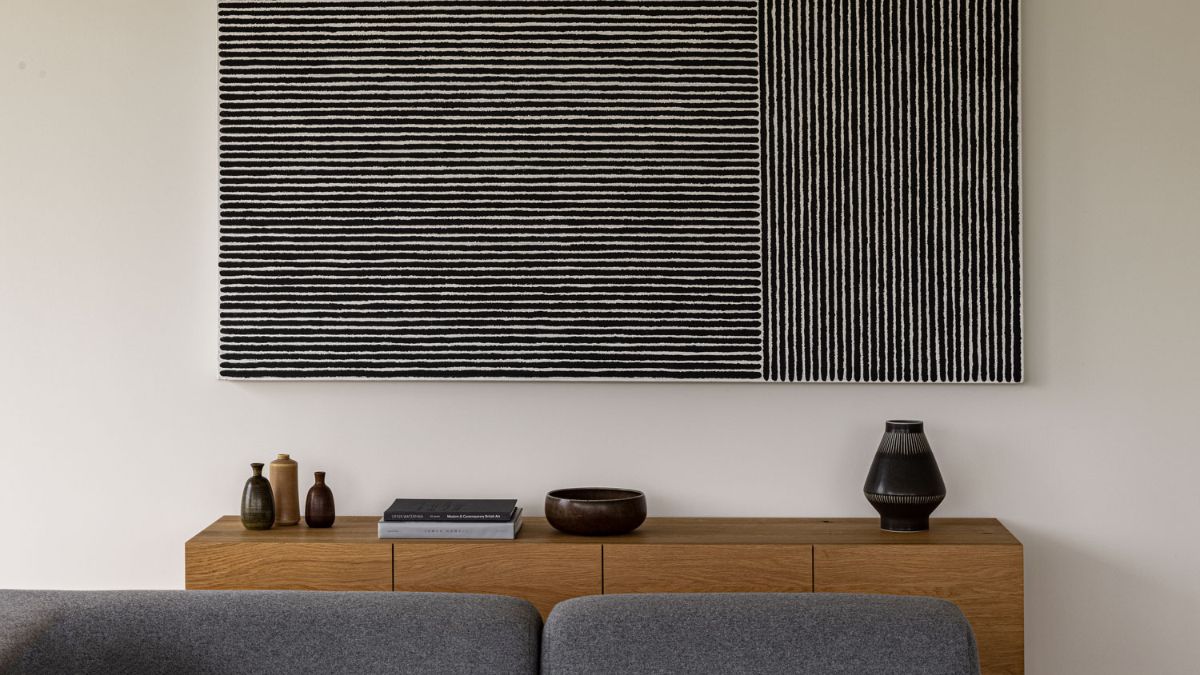 The living room furnishings, minimalistic artifacts, and colorless wall complement each other wonderfully.