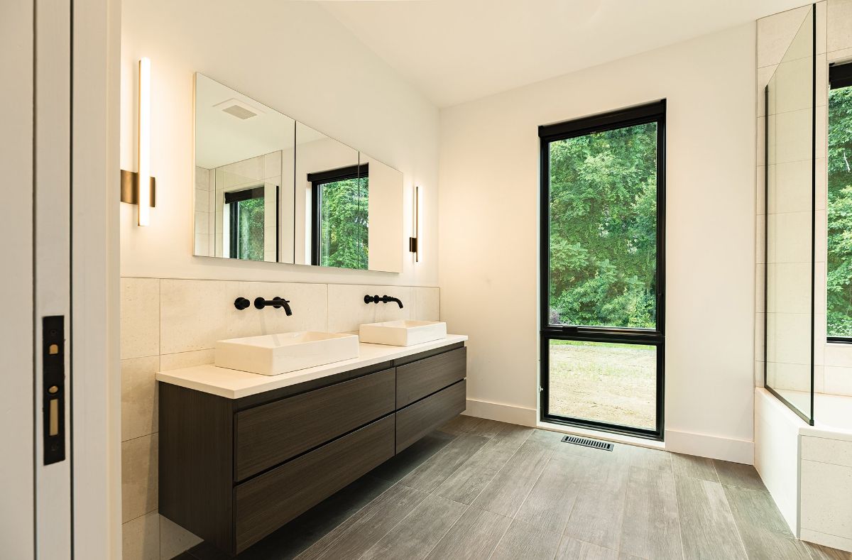 The bathroom is lit by wall lights, and the floating vanity has an overmount sink.