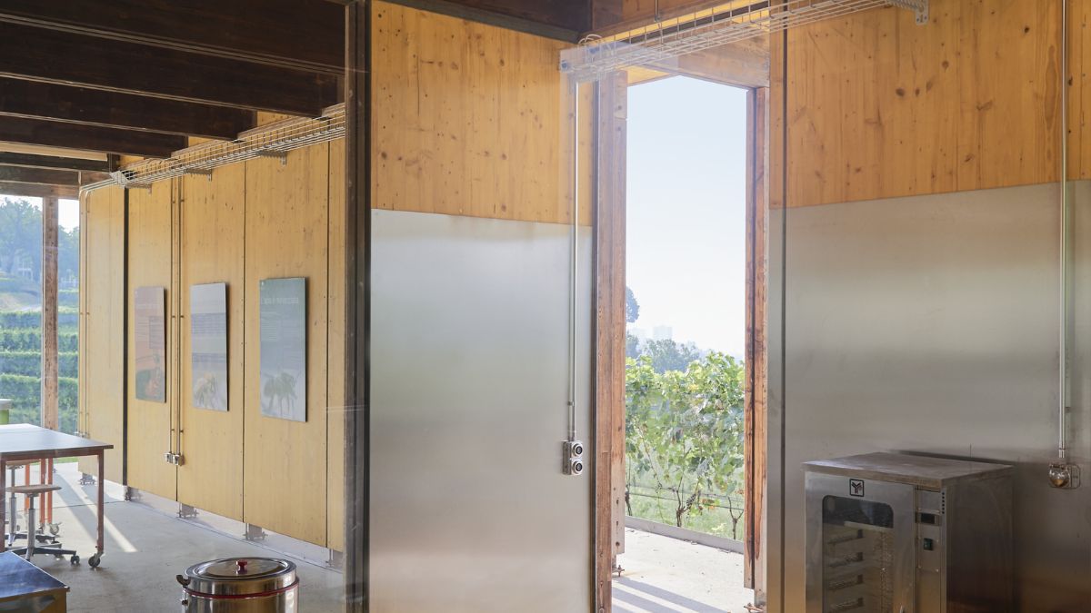 A view of the adjacent rooms with exposed brown beams and stainless steel appliances.