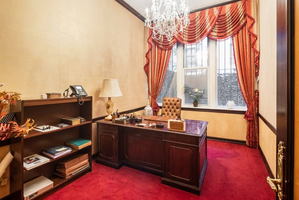 Home office with a wooden desk paired with a leather tufted chair.