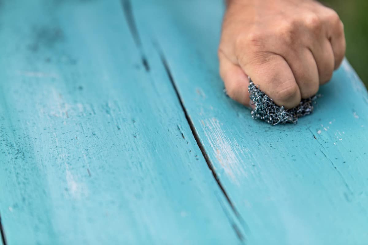 Distressing wood plank painted in blue chalk paint.