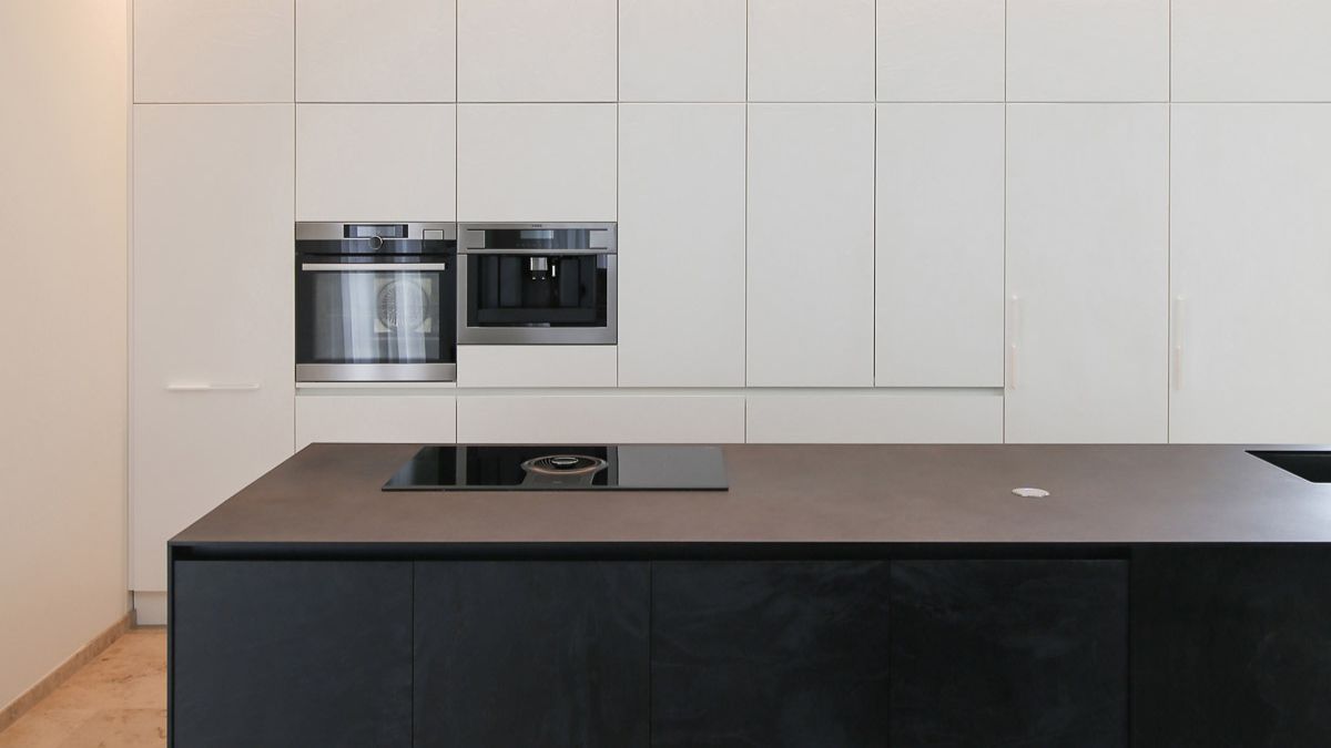 The kitchen island's black furniture and the embossed texture of their facades both stood out from the light background.