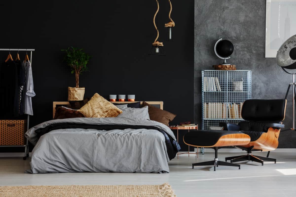 Black primary bedroom with platform bed and lounge chair.