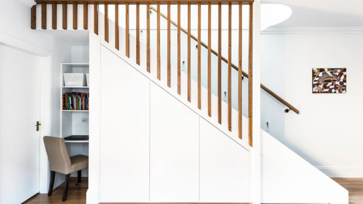 A desk or workspace is located next to the stairs.