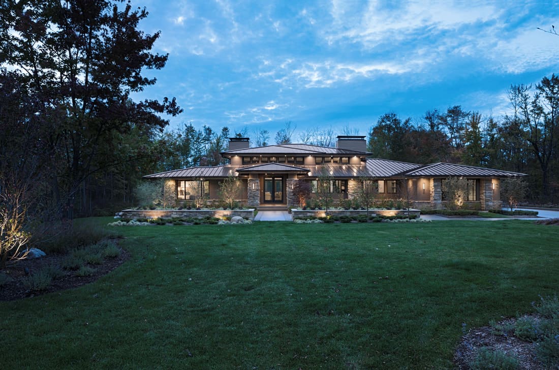 At night, the prairie modern home is complemented with ambient lighting that highlights its stone exterior.