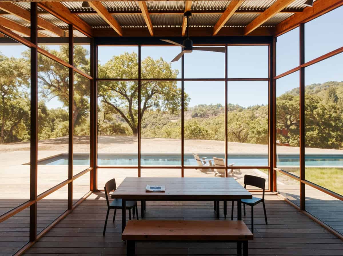 The dining area is surrounded by glazed walls overlooking the pool deck.